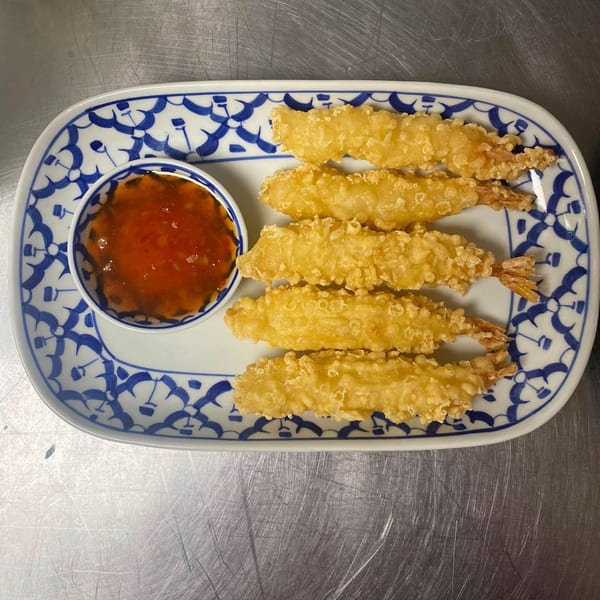 Five crispy fried shrimp with sweet chili dipping sauce on a blue and white patterned plate.